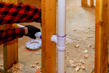 Close up on t joint and pipes for a home sewage system, in wood wall, drain and vent plumbing system