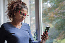 Sad Black Woman Near Window Reading Phone Message