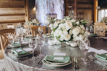 on the banquet table are plates, cutlery, glasses and flower arrangements