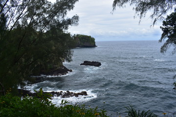 Waves Crashing on Rocky Shore in Hawaii white foam as the waves wash over the rocks under a blue sky