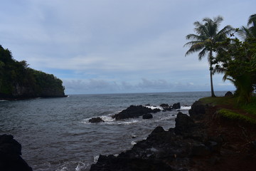 Waves Crashing on Rocky Shore in Hawaii white foam as the waves wash over the rocks under a blue sky