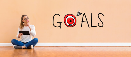 Wall Mural - Goals with target with young woman holding a tablet computer