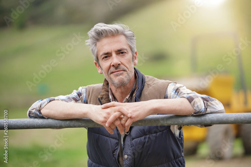 Fotografía Attractive farmer leaning on fence looking at camera