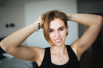 beautiful happy woman with tattoo on hand straightens her hair, looks into the camera and laughs.