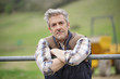 © goodluz - Attractive farmer leaning on fence looking at camera