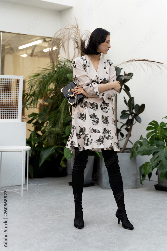 Asian chinese model girl wearing a dress with black boots and handbag Stock Photo | Adobe Stock Asian chinese model girl wearing a dress with black boots and handbag Stock Photo | Adobe Stock