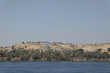 Blick auf ein typisches Dorf in Ägypten nahe Luxor am Ufer des Nil, blaues Wasser, blauer Himmel, Wüste