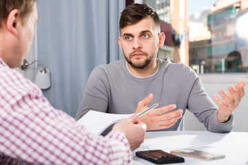 Sticker - Troubled man discussing documents with male at home table