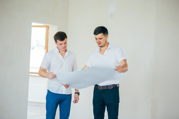 Two business men or engeners working and discussing plane house drawing during the construction and repair process indoor. Architect blueprint Order Customer Industry