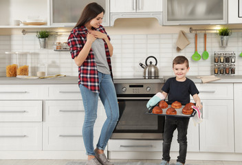 Canvas Print - Cute boy treating mother with oven baked buns in kitchen