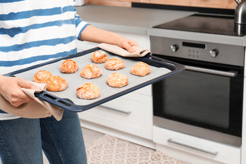 Canvas Print - Young woman with sheet pan of oven baked cookies in kitchen, closeup