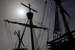 A caravel, an old sailing ship in front of the bright sun in the back light.