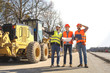© Vasiliy - male workers engineers in helmets talking near the bulldozer and excavator