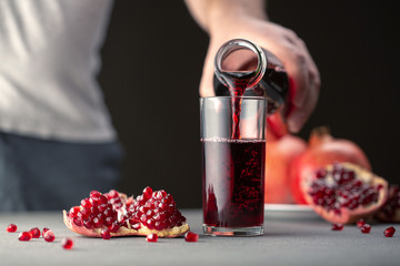 Male hand pouring pomegranate juice into a glass.