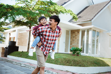 Wall Mural - son enjoy riding on his father's back in the morning at their house