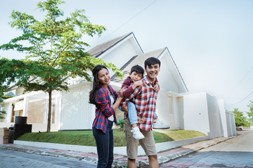 Wall Mural - father piggyback ride with his son in front of the house playing enjoying their time in the morning