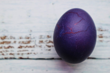 Purple cracked easter egg on wooden background closeup