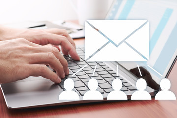 Businessman sending email for customers. Laptop at wood table.