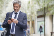 © goodluz - Businessman commuting on foot with cellphone
