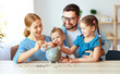 © JenkoAtaman - financial planning   family mother father and children with piggy Bank at home.