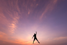 Silhouette Of Jumping Man On Sunrise Background