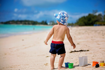 Wall Mural - Cute baby boy playing with beach toys on tropical beach