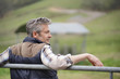 © goodluz - Farmer leaning on fence looking out in field