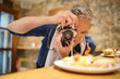 © goodluz - Mature photographer taking photos of tapas plate in Spanish restaurant