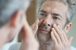 © goodluz - Portrait of mature handsome man looking in mirror at home