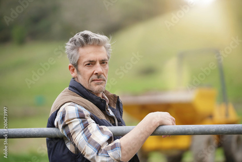 Fotomural Attractive farmer leaning on fence looking at camera