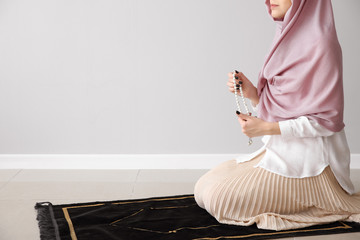 Wall Mural - Muslim woman praying near light wall