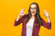 © denis_vermenko - Portrait of a satisfied girl in casual showing ok gesture isolated over yellow background.
