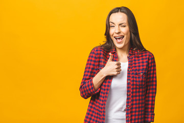 Portrait of a pretty happy woman in casual posing isolated on a yellow background. Thumbs up.