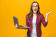 © denis_vermenko - Portrait of an excited young beautiful girl holding laptop computer and celebrating success isolated over yellow background.