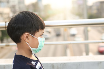 A 5 years old boy wearing a medicine healthcare mask on the street.