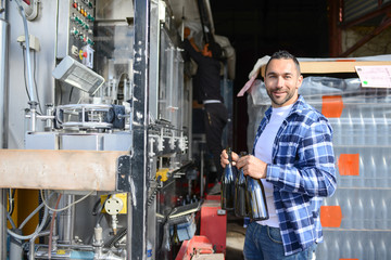 Wall Mural - young man wine maker working filling wine bottle with automatic bottling machine