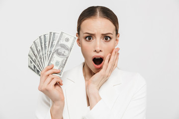 Sticker - Photo of shocked businesswoman 20s wearing elegant jacket holding fan with dollar money banknotes