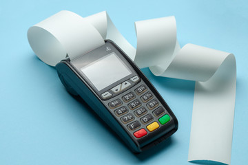 terminal cash register machine pos for payments and long roll cash tape on blue background.