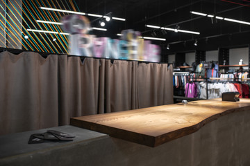 Modern clothes shop with concrete cash desk with wooden tabletop