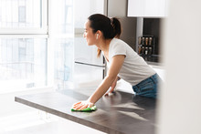 Portrait Of Charming Asian Girl Cleaning Table With Detergent And Rag In Kitchen At Home