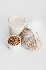 Poster - chickpea in bowl and cheesecloth near vegan chickpea milk in glass on grey background