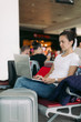 © Rychko Yevhen - Young female passenger using laptop computer at airport while waiting for her flight