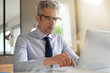 © goodluz - Businessman wearing glasses working in contemporary office