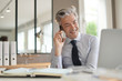 © goodluz - Businessman talking on cellphone in contemporary office
