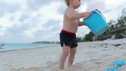 Wall Mural - Cute toddler baby boy playing with beach toys on tropical beach