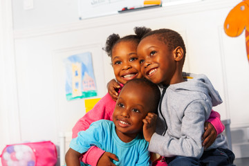 Wall Mural - Three happy little black kids close portrait hug