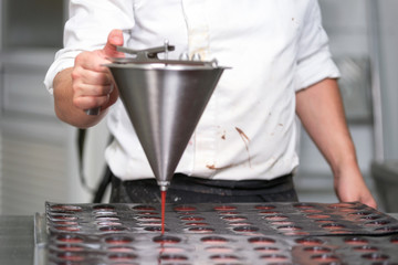 Wall Mural - Pastry chef pouring strawberry marmalade, working at kitchen of pastry shop .