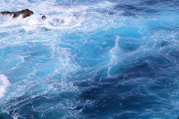 Blue gushing ocean. The waves of the ocean form a lot of white foam. Cropped shot, horizontal, a lot of free space for text, without people. Concept of nature and travel.