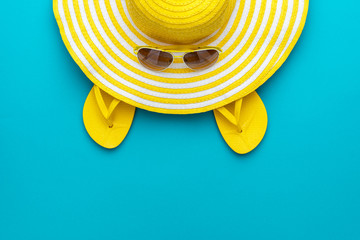 top view of yellow sunglasses, striped retro hat and flip-flops