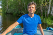 © Tatyana_Andreyeva - Handsome middle-aged man sitting at boat stern and floating along northern river on beautiful landscape background in summer sunny day. Travel concept. Chernaya river, Karelia, Russia